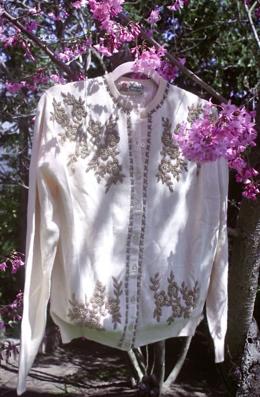 White wool cardigan with beaded floral embroidery hanging outdoors